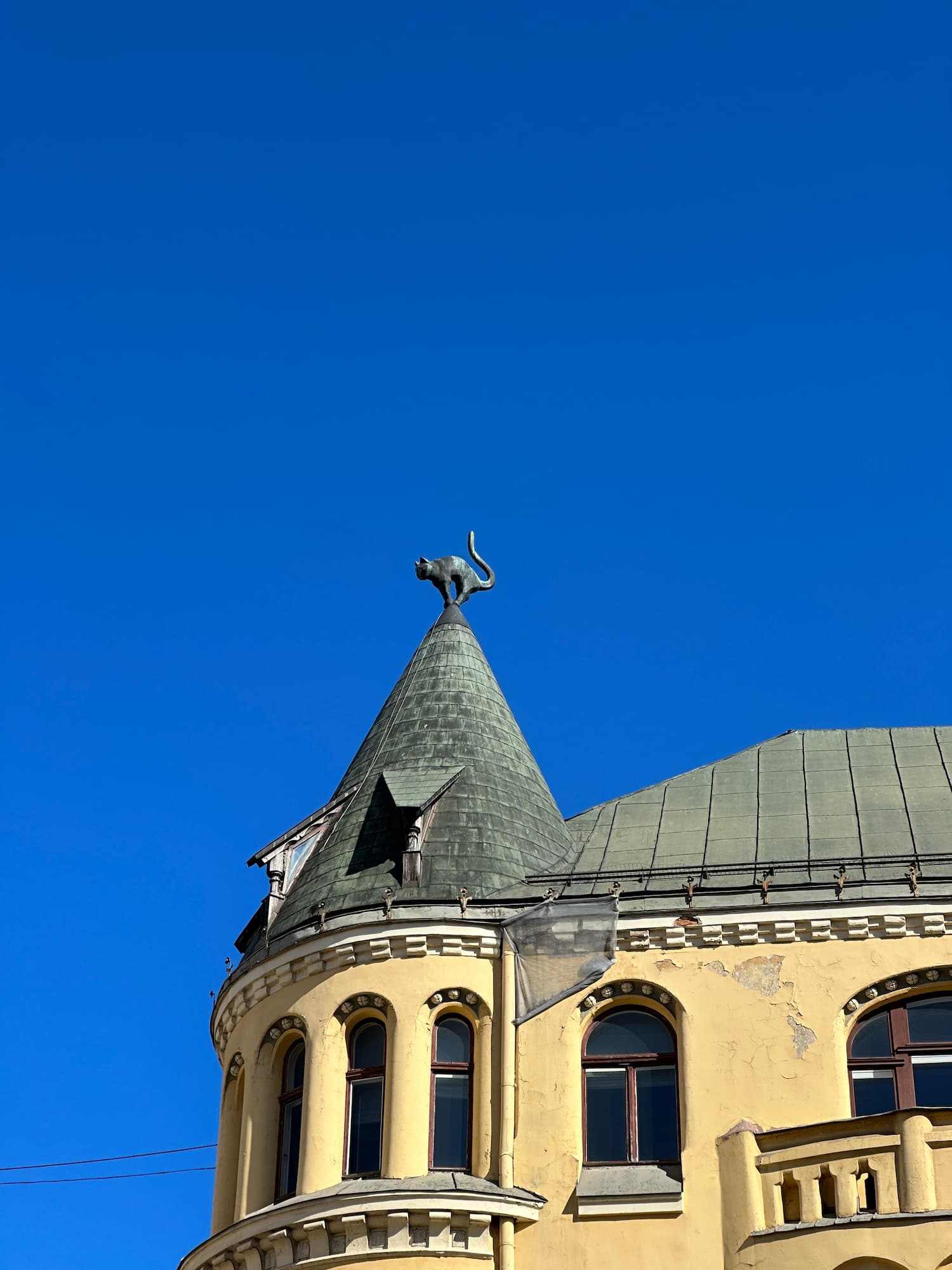 A building with a sculpture of a cat with an arched back on the roof