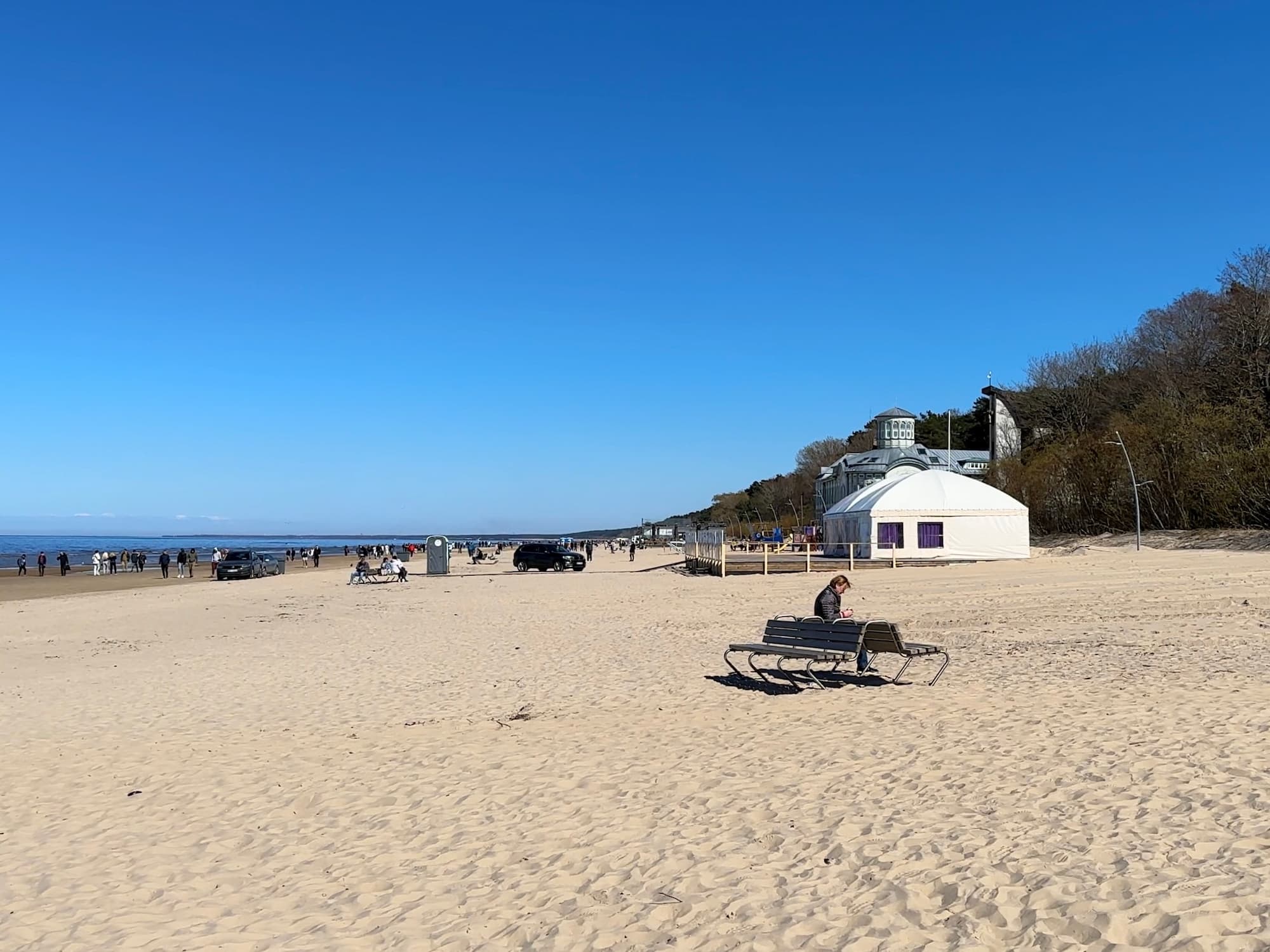 Two benches on a beach. A woman is sitting on one of them