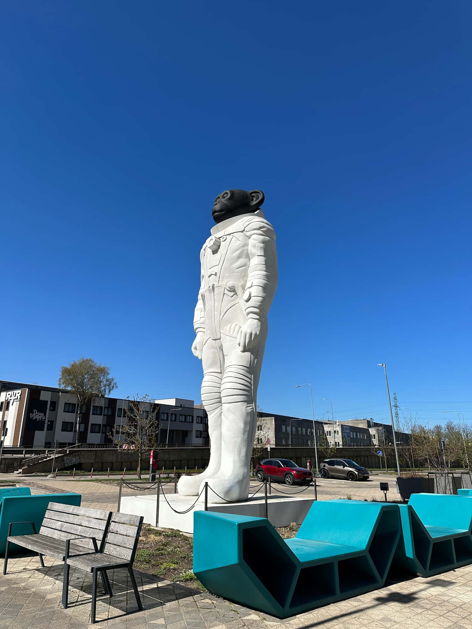 The sculpture next to a bench with terraced houses in the background